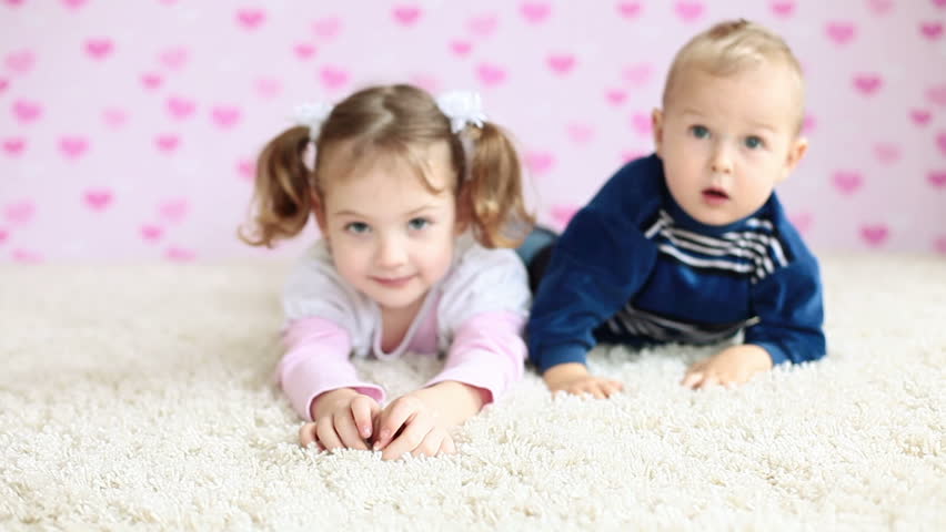 Brother and sister lying on the floor and looking at camera
