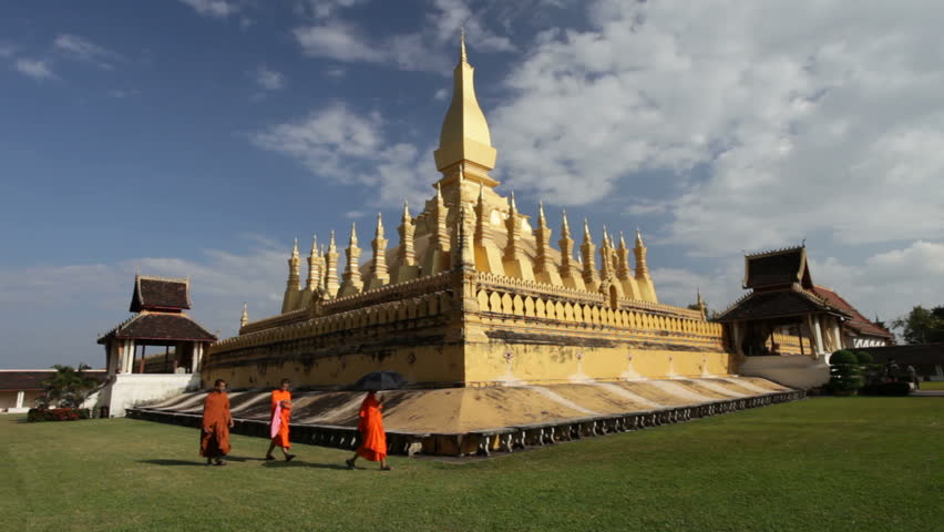 VIENTIANE - OCTOBER 31: Three monks walk in front of the golden pagoda of