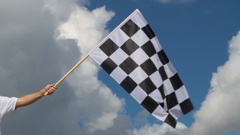 Hand holding a checkered flag on a raceway
