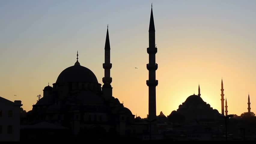 Mosques against sunset. Pan over minarets, domes, roofs 