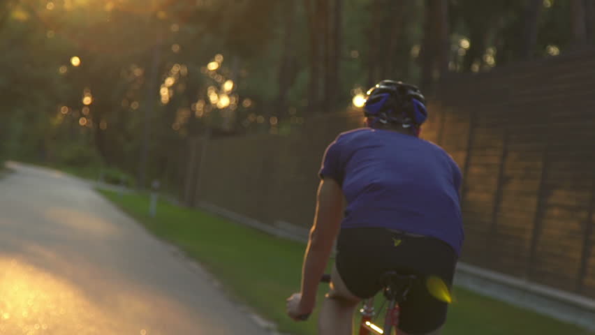 Cyclist riding a bike on an open road to the sunset