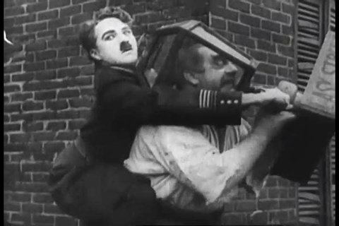 A clip of Charlie Chaplin in the silent film, Easy Street in 1920s, shows Charlie trying to free someone\xCDs head from inside a lamppost. (1920s)
