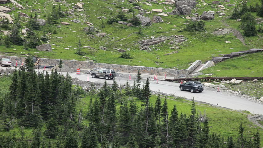 Mountain road under repair through steep terrain, tight turns and forest in Glacier National Park, Montana. Going to the Sun famous road for sightseeing and adventure. Logan