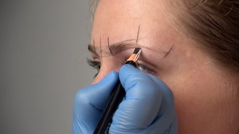 Microblading procedure. Master marks out customer's eyebrows