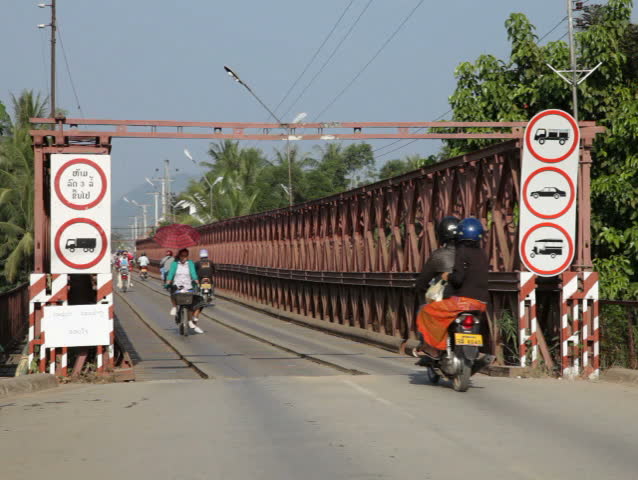 LUANG PRABANG, LAOS - OCTOBER 27: Moterbikers cross an old bridge over the