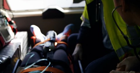 Emergency medical technician taking car an injured woman inside ambulance car