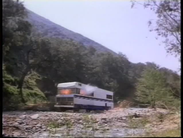 Wide shot of trailer blowing up in wooded area