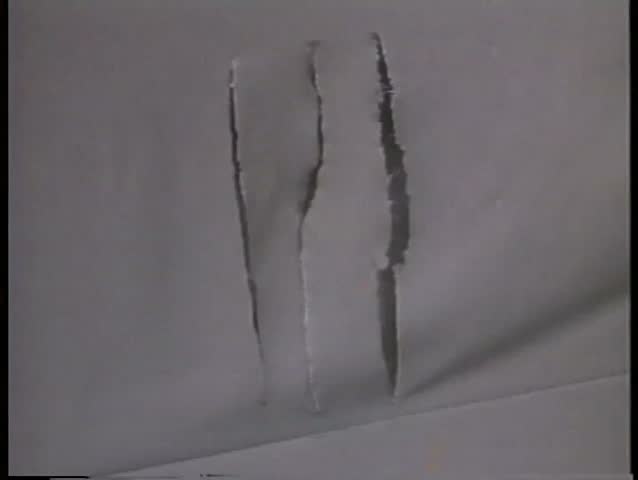 Close-up of bloody hand pushing through slit fabric