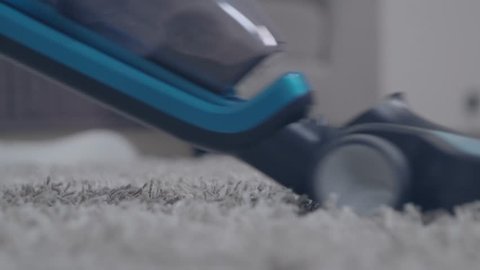 Detail 4k shot of a vacuum cleaner cleaning hairy grey carpet in a bedroom. Housekeeping process.