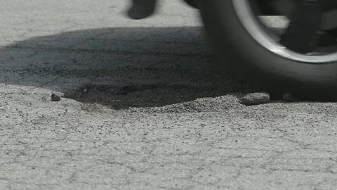 Tire Hits Pothole Close Up Slow Motion. a low close up of suv tires hitting a pothole on a road. Driving from right to left
