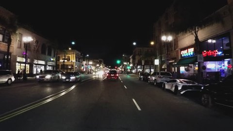 PASADENA, CA/USA: February 21, 2016- A night time driving shot through the downtown shopping district in Pasadena California. A vehicle passes by shops, restaurants and night life.