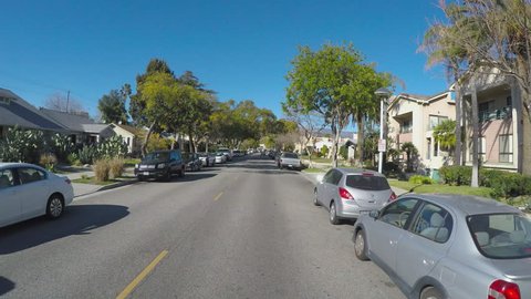 GLENDALE, CA/USA: February 21, 2016- Point of view driving vehicle shot through a residential neighborhood street. The vehicle passes by apartments and homes in a suburban part of town.