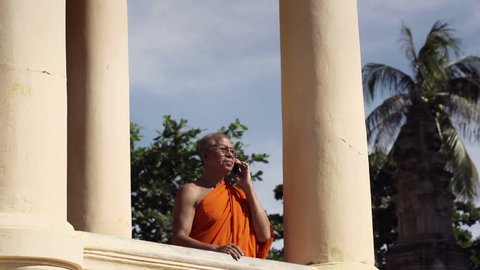 Senior Asian Buddhist monk speaking with cell phone in monastery, Phnom Penh, Cambodia, Asia. With Model Release