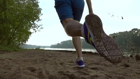 Slow motion steadicam video of runner's feet on on wet sand of riverside, 240 fps