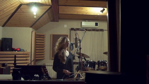 Beautiful girl sings in a recording studio - 4K shot with dolly.