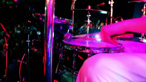 Drummer in white costume holds drumsticks and play, closeup view