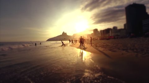 Silhouettes of carioca Brazilians playing altinho beach soccer at sunset on the shore of Ipanema Beach in Rio de Janeiro, Brazil