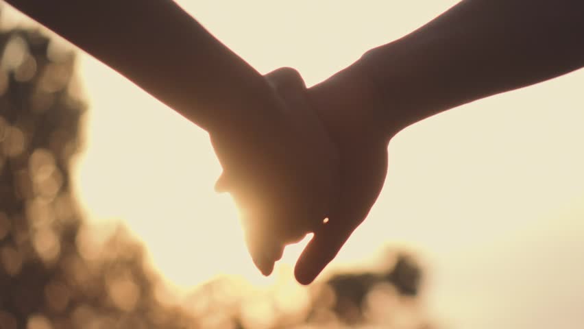 Close up of two Lovers Joining Hands. SLOW MOTION 240 fps. Detail Silhouette of Man and Woman holding hands over the Sunset Lake Background. Couple Trust, Love and Happiness concept.