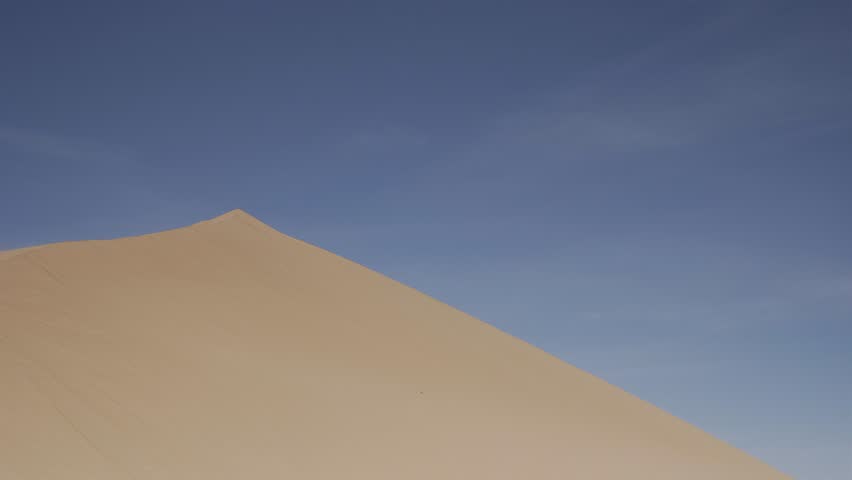 Photographer Desert Sand Dune / Multiple clips of a young male climbing up a sand dune and taking a picture of the desert view. At the end he walks down and takes more pictures.