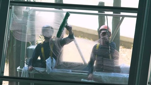 NICE, FRANCE - JUNE 19, 2016: Window cleaners washing glass. Brave high rise workers cleaning window, dangerous trade, risk to health, qualified service, manual labor. Men working climbing at height
