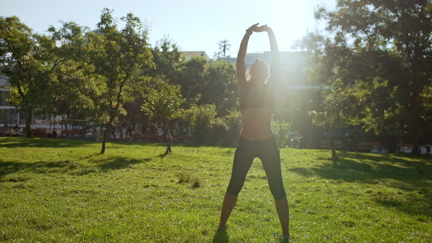 Young beautiful sportive girl training in park. Slow motion.