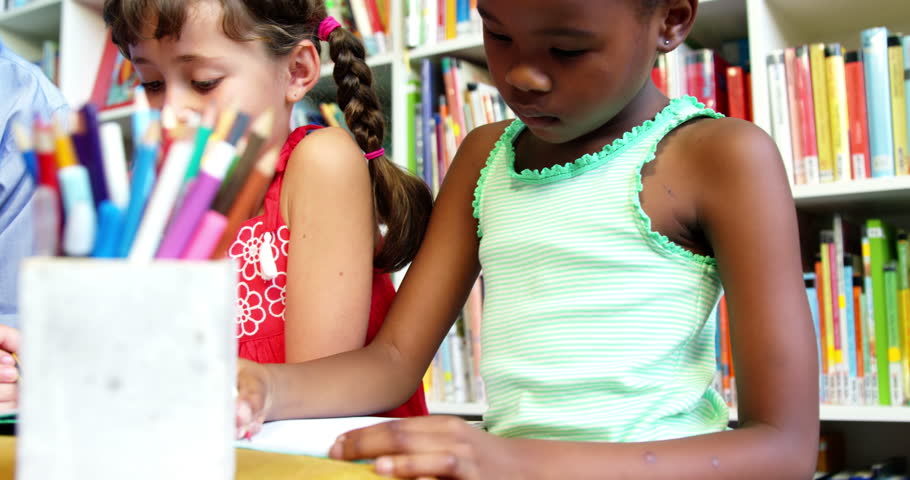 Slow motion of teacher helping schoolkids with his homework in library at school 4k