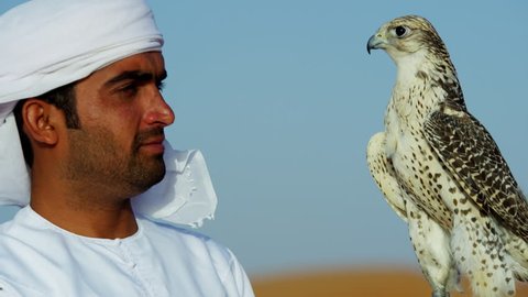Middle Eastern falconer in desert with his bird of prey