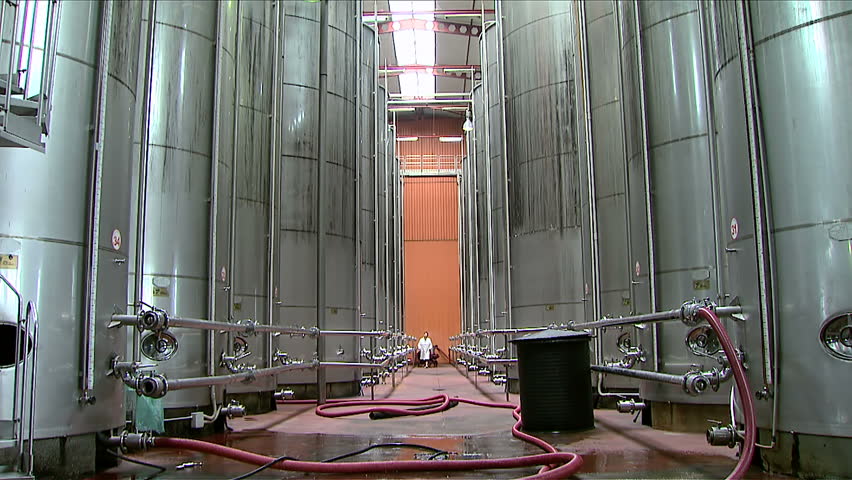 Worker monitors inside the wine factory. Factory for wine production. Silos for the storage of wine in factory