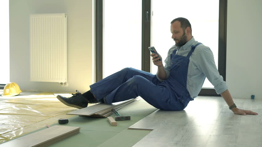 Male worker using smartphone during break from work at new home

