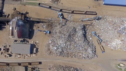 Iron raw materials recycling pile, work machines. Metal waste junkyard. Excavators diggers works on a garbage dump .View from above.