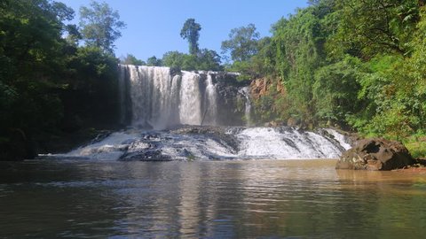  Impressive waterfall surrounding by tropical trees under clear blue sky