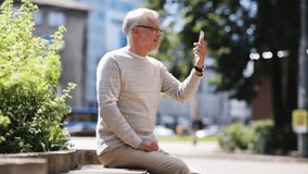 technology, people, lifestyle and communication concept - happy senior man having video call on smartphone in city