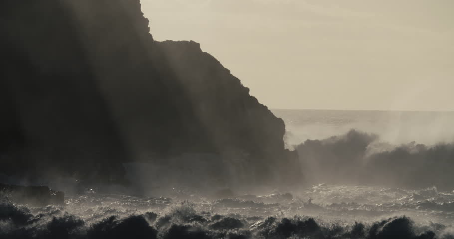 Blue waves roll into the coast of Hawaii and crash into the shore in slow motion during a big storm. (Hawaii 2010s)