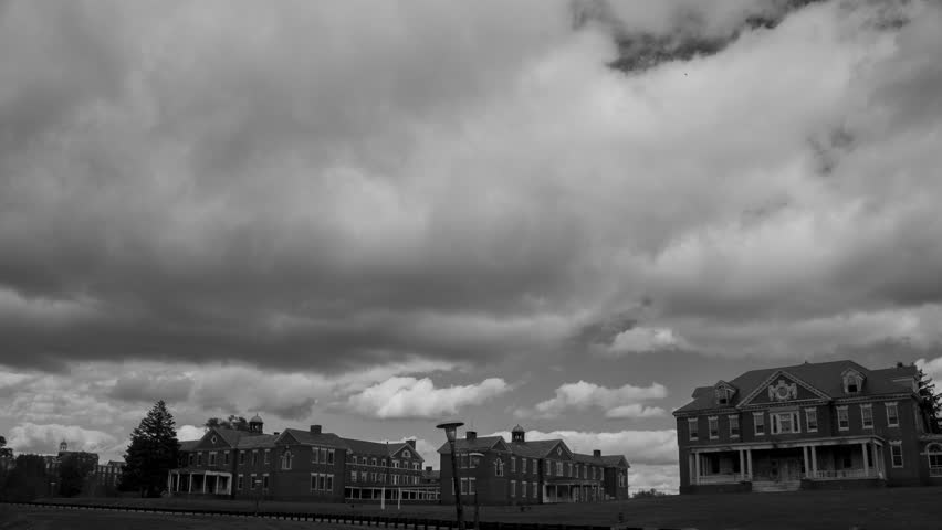 Black & white time-lapse of clouds over old brick buildings