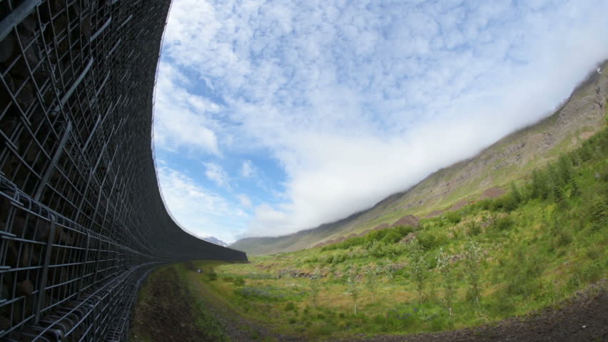 Avalanche barrier over Neskaupstadur summer blue sky Iceland fish eye