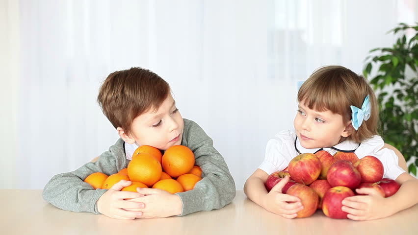 Laughing children with fruit at the table