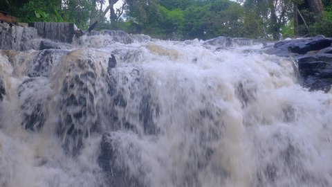 Close-up of white water flowing over huge black rocks.