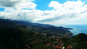 Flight over ocean mountain village city. Portugal Madeira Funchal 4k travel video background. Aerial drone view of coast, buildings, forest hills, seashore