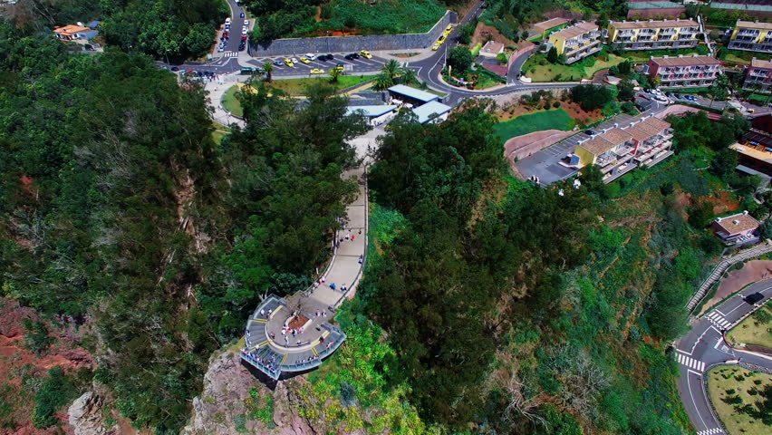 Flight over city Funchal. Portugal Madeira village 4k travel video background. Aerial view of city, cliff and forest, walking peple