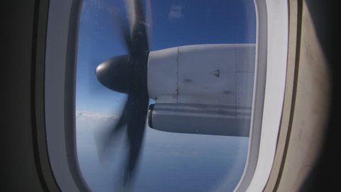 Turboprop propellor engine viewed through window of passenger airplane.
