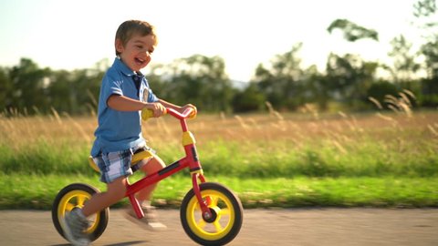 4k footage , laughing little boy having fun riding his bicycle on sunny afternoon
