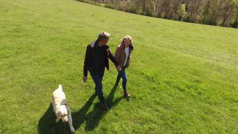 Aerial Shot Of Mature Couple And Dog On Walk In Countryside 