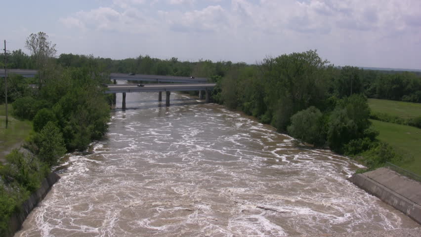 Water flowing under a bridge where cars pass over
