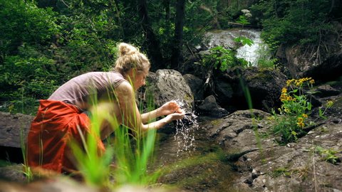 Cinemagraph of a Woman Cleaning her Hands in Wild Fresh Water Stream Adlı Stok Video