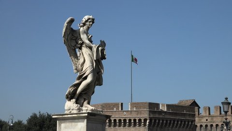 ROME, ITALY: Zoom to Italian flag past angel statue, one of 12 angel statues on Ponte Sant'Angelo, leading to  Castel Sant'Angelo.  End on flag.