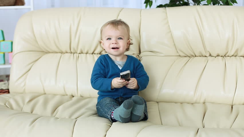 Baby boy with phone sitting on the couch