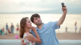 Beautiful couple taking selfie giving kiss on the beach on summer