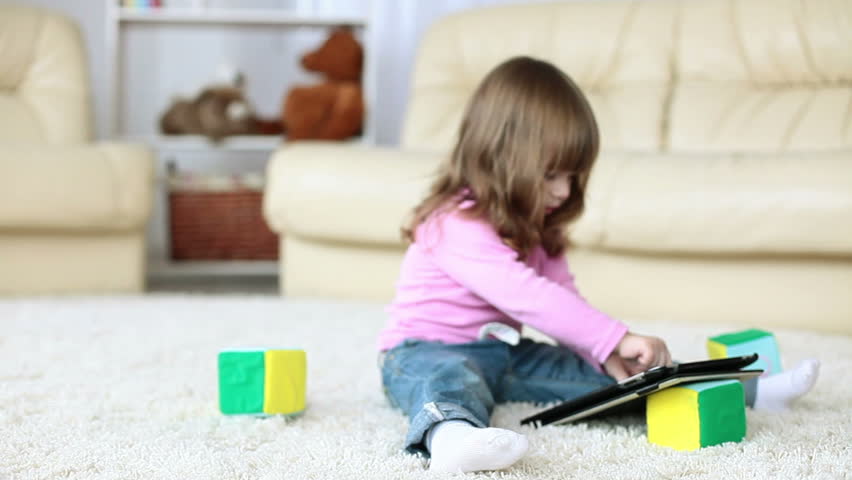 Baby girl with tablet PC siting on the floor
