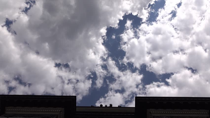 POV walk looking up to coffer vault of Triumphal Arch of Moscow, glide camera. Extreme low angle shot, bright white clouds on blue sky. Shaded arc ceiling, pass through opening