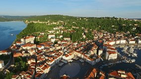 Flight over old city Piran in Slovenia, aerial panoramic view with old houses, roofs, St. George's Parish Church, Tartini Square, fortress and the sea. 